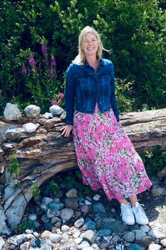 Nele Winter lehnt im rosa Kleid und Jeansjacke an einem Baumstamm